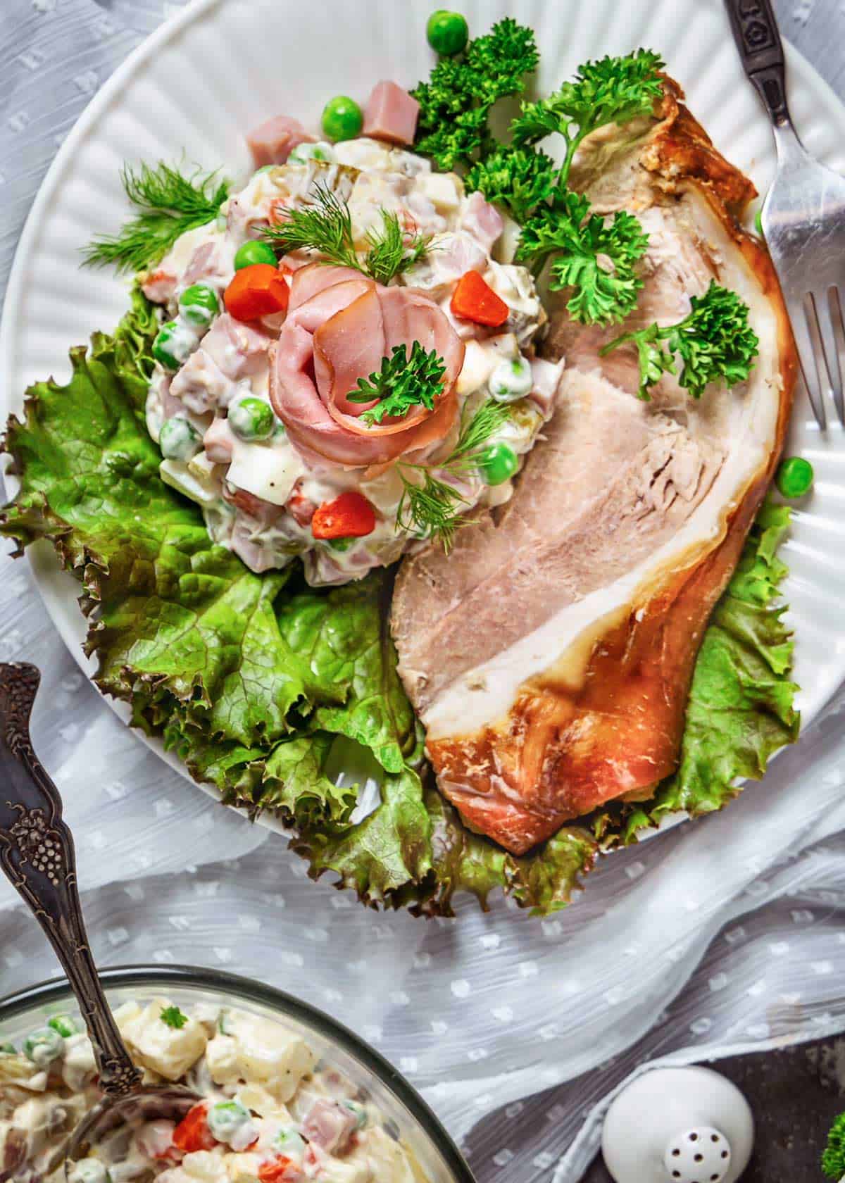 A serving of Russian salad with a slice of pork shoulder roast with crackle.